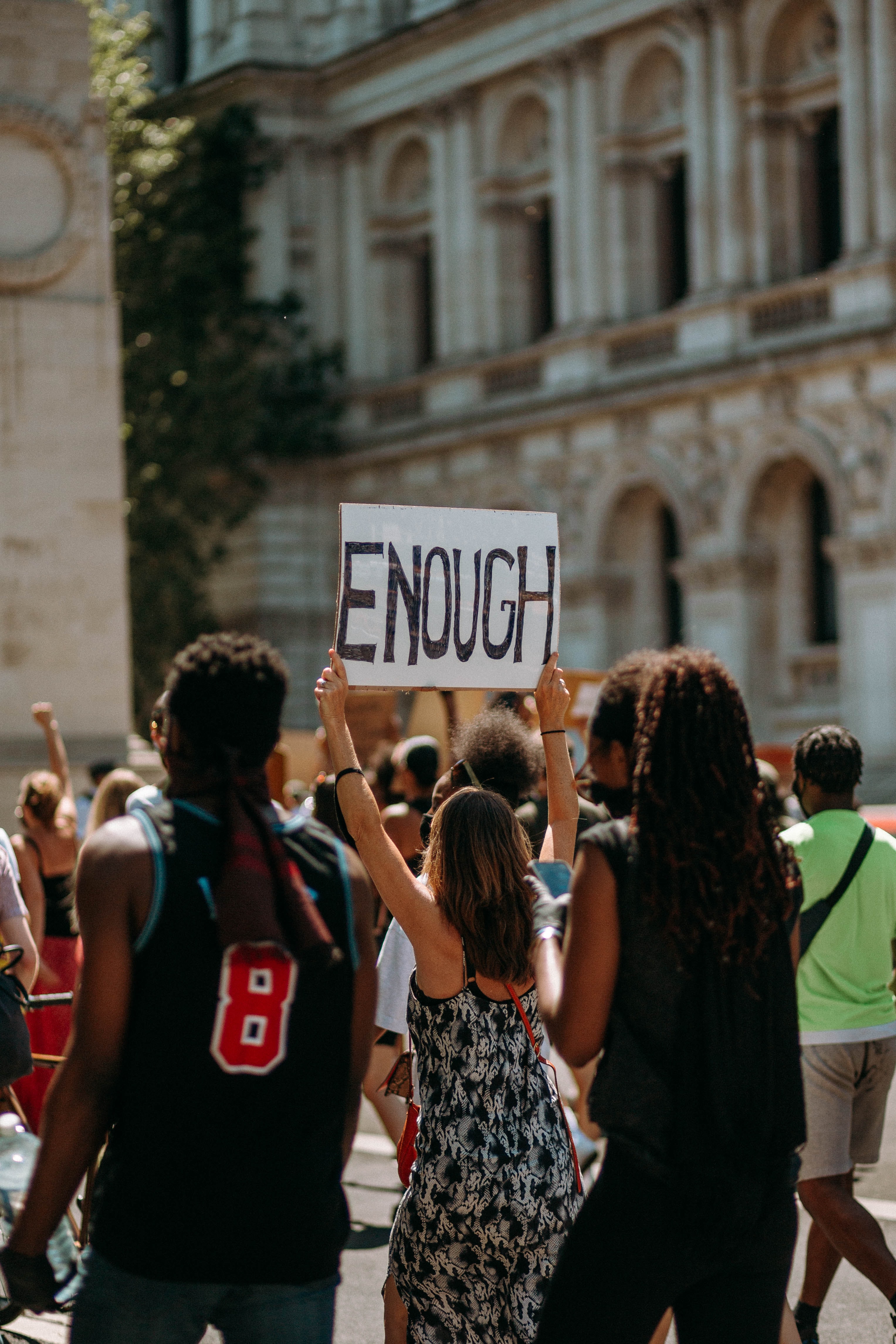 A croud of people with a person holding a sign that says enough.